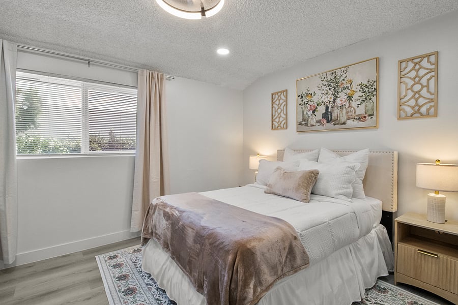 Cozy queen bed with fresh linens, nightstands, and room-darkening window coverings.