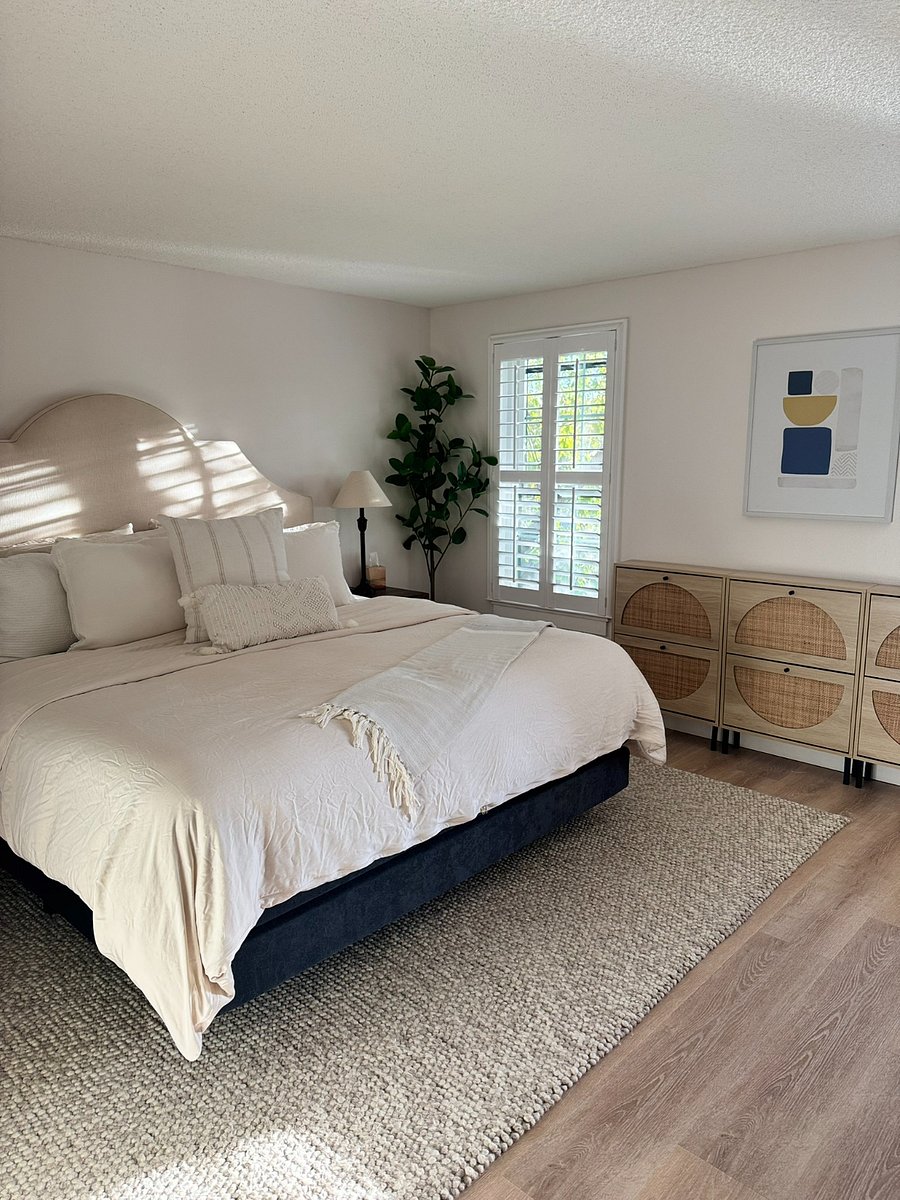Bright and airy primary bedroom with modern furnishings, a comfortable king mattress, and plantation shutters for a restful night's sleep. Includes an en-suite bath and walk-in closet.