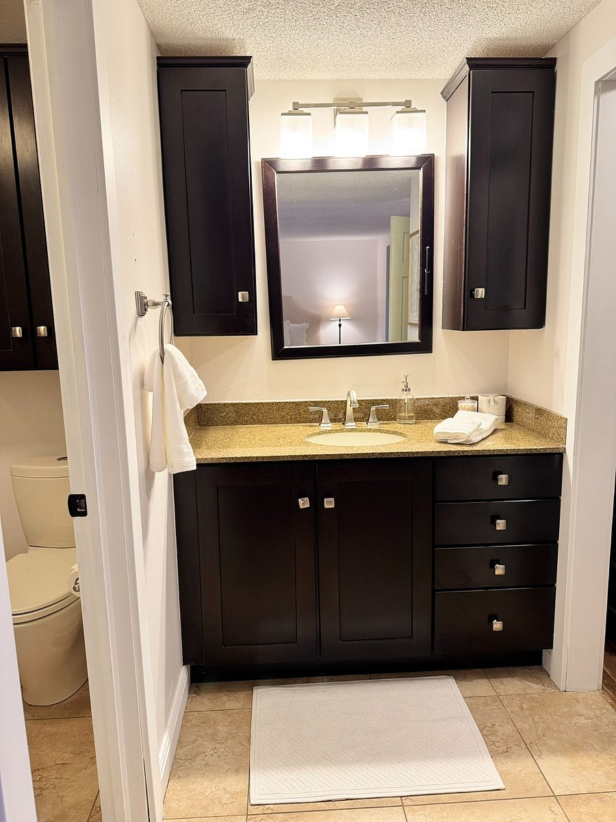 En-suite primary bathroom with a large vanity, fresh linens, ample cabinet storage for your toiletries, and a full tub-shower combination.