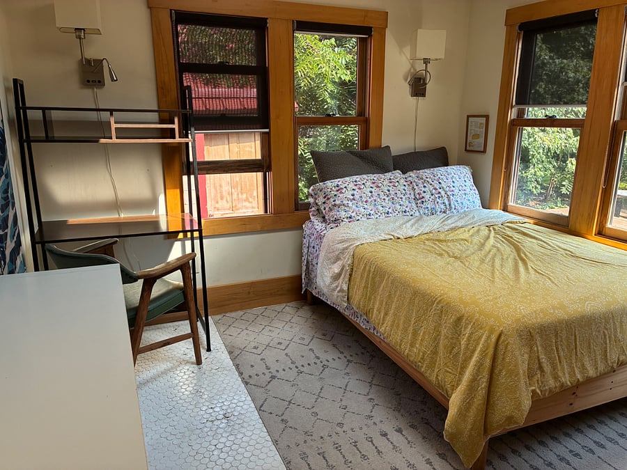 The sun room features a full-sized bed, excellent lighting, and a view of the backyard.