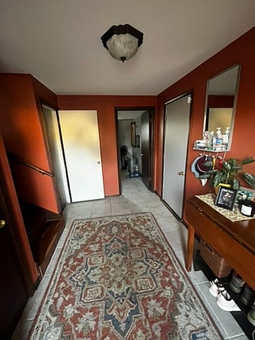 View from front door into entryway. Left goes upstairs to the living room and downstairs into homeowner's quarters. Straight ahead is the laundry room, to the right is the entrance into the garage. 