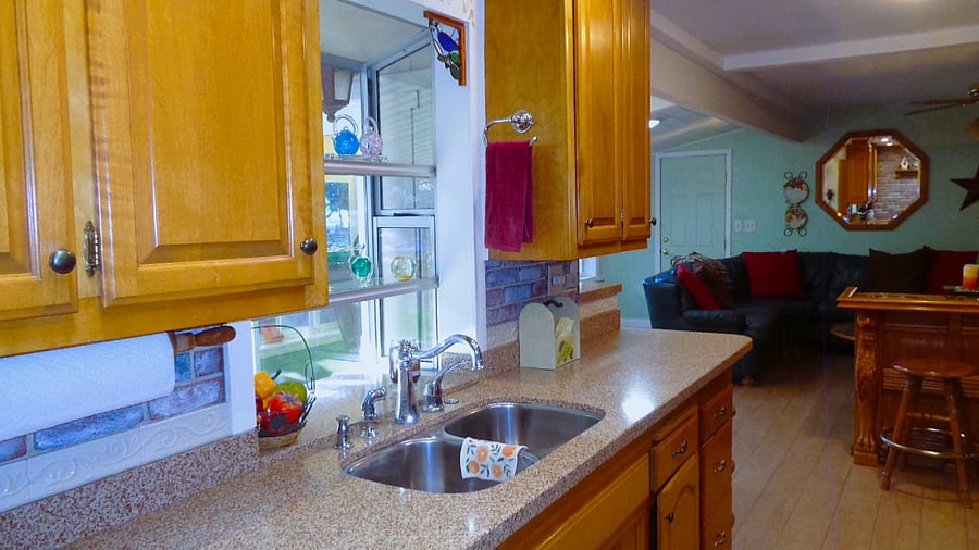 Sparkling double sinks and garden view window in the kitchen. All plates, cooking utensils and pots and pans are ready for cooking for about 6 people.