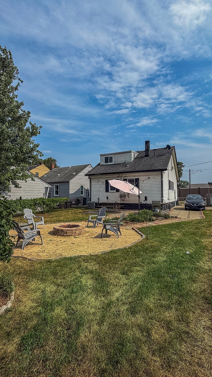 Spacious backyard with fire pit seating, patio, picnic table and BBQ grill.