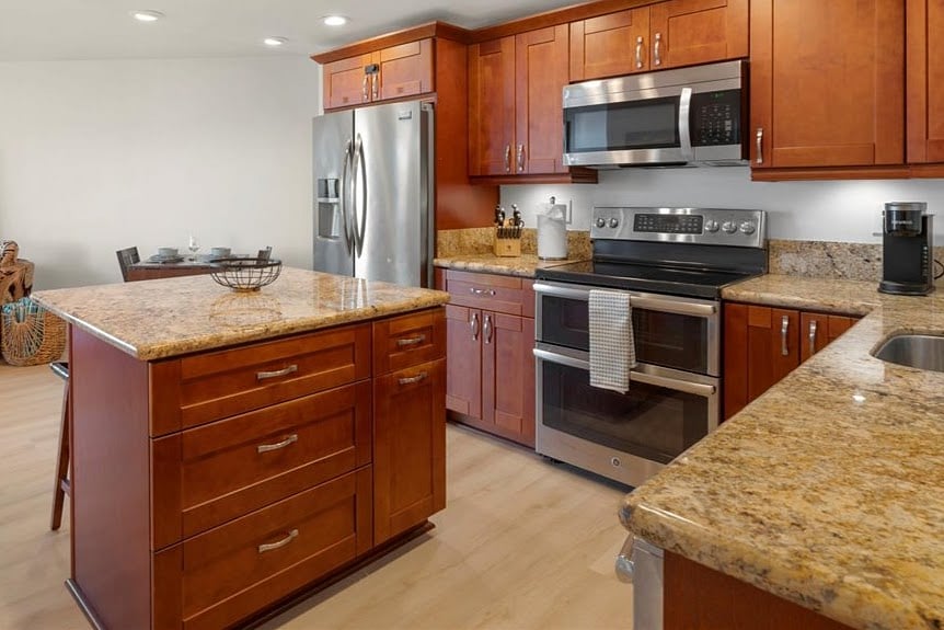 A spacious kitchen fully equipped for easy island dining. Featuring warm wood cabinetry, granite countertops, and plenty of room to gather.