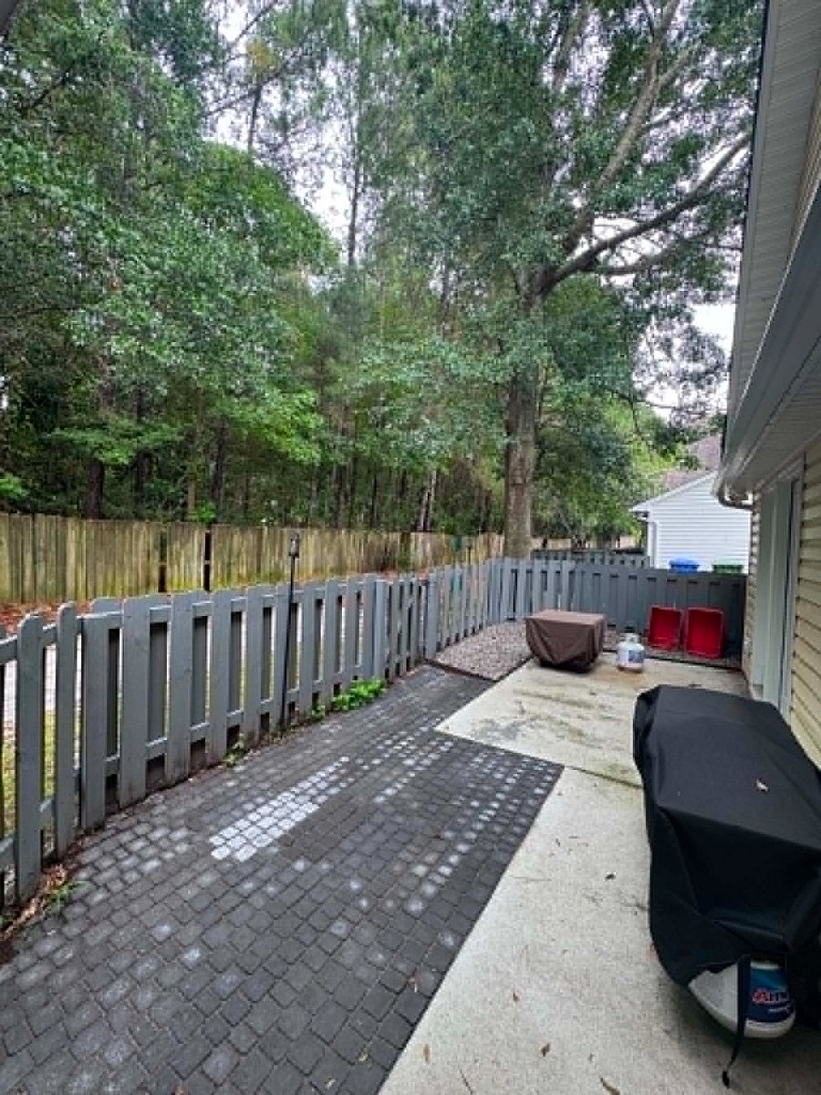 Fenced in patio with tiki torches, fire pit, and Blackstone grill