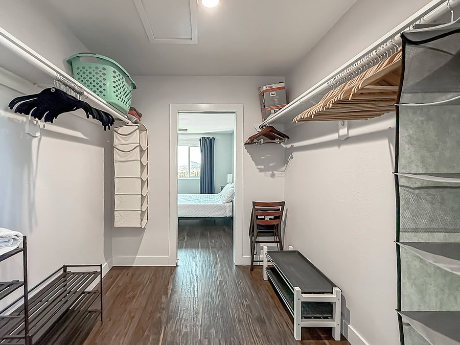 Interior - Spacious furnished walk-in closet with custom shelving, hanging storage, hardwood flooring, and view to bedroom - organized and move-in ready