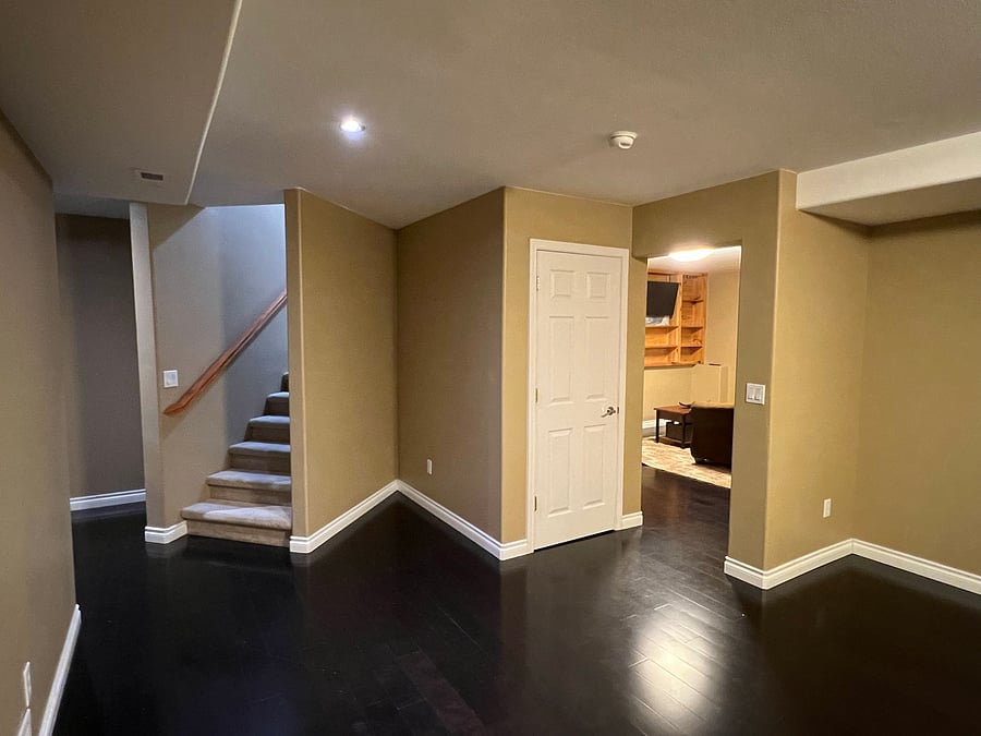 Basement: These stairs take you down into the gym. The bathroom is behind me (in the gym). If you go through the little doorway on the right, you enter the living room, where the dining room will be to your right and the bedroom is to the left.