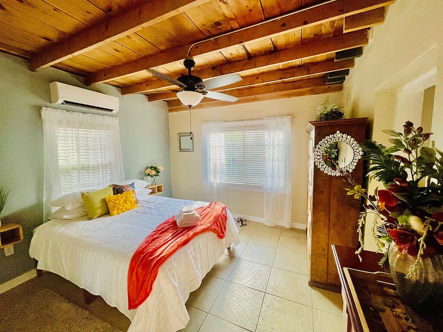 Queen-sized bed with floating night stands, a wooden wardrobe and full length mirror.'
