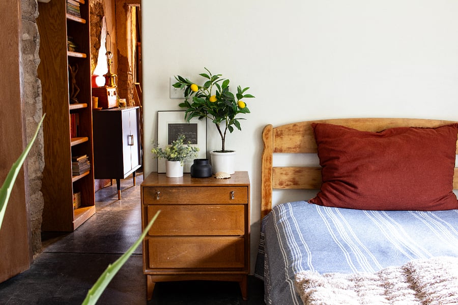 FULL-SIZE BED WITH NIGHTSTAND AND KITCHEN BEYOND