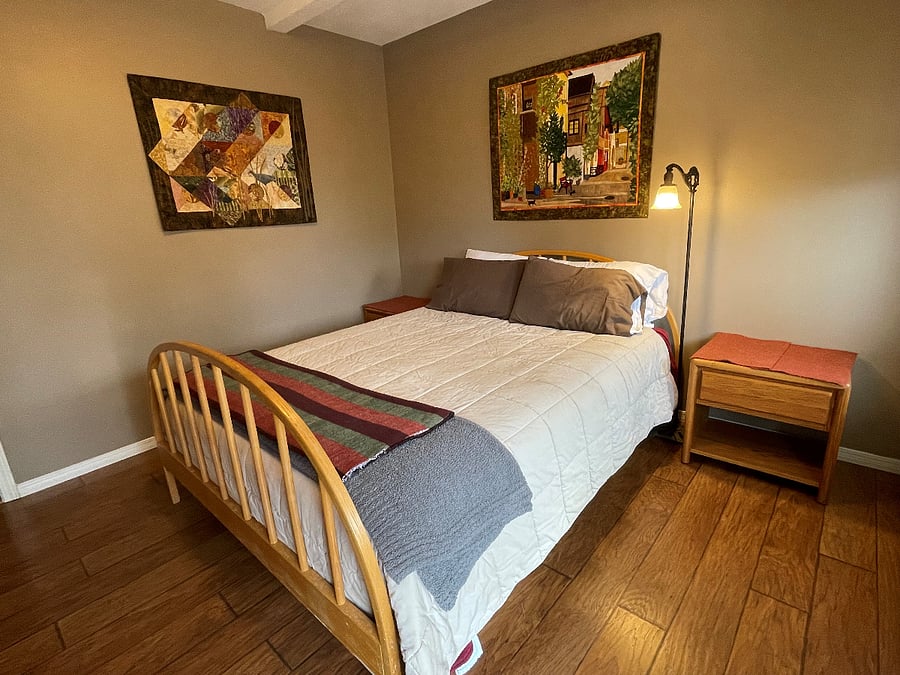 suite bedroom with queen bed, private deck, and attached bath with tub