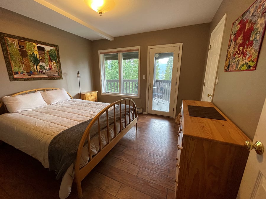 suite bedroom with queen bed, private deck, and attached bath with tub