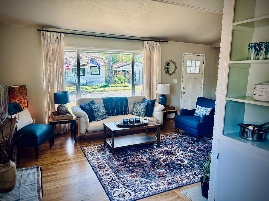 The living room has large windows with drapes for privacy