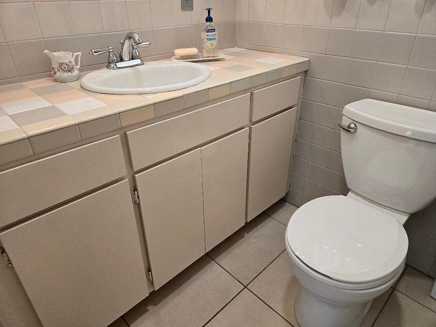 Semi-private bathroom with vanity, toilet, and cupboards for storage