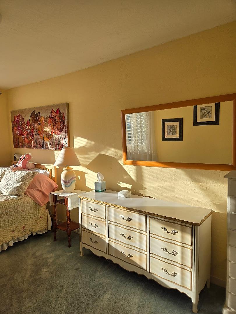 Bedside table, dresser and mirror next to bed