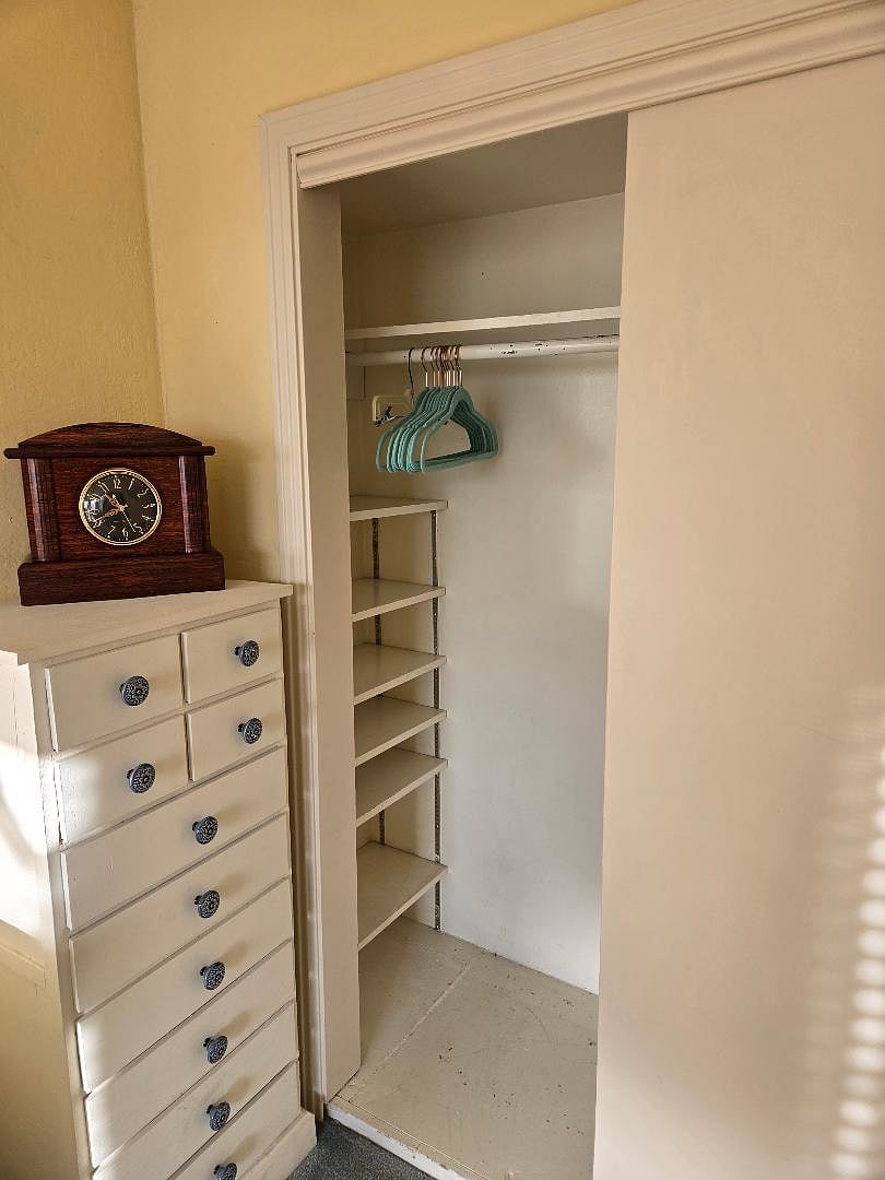 Chest of drawers, vintage clock and closet with shelving