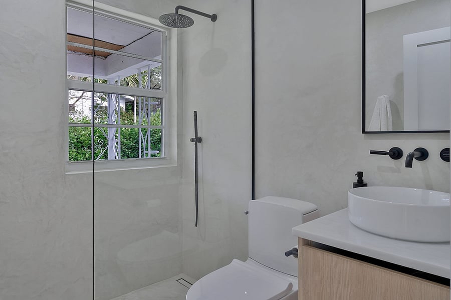 Bathroom 3 which also serves as the powder room. Microcement shower and walls with white marble vanity. 