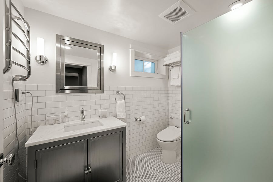 Bathroom with vanity, mirror, walk-in shower, and bright tile finishes throughout.
