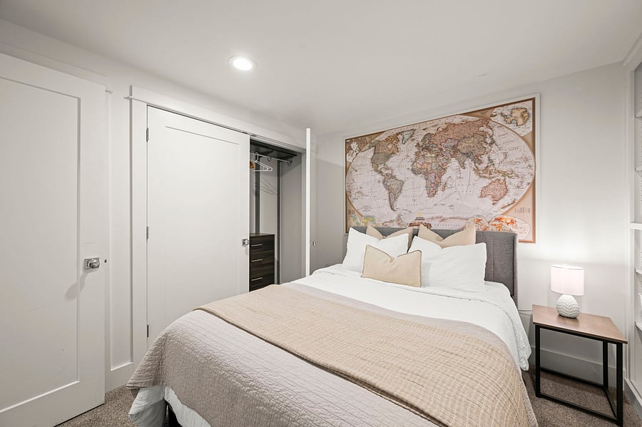 Bedroom looking toward door and closet area, showing nightstand and clean, modern finishes.