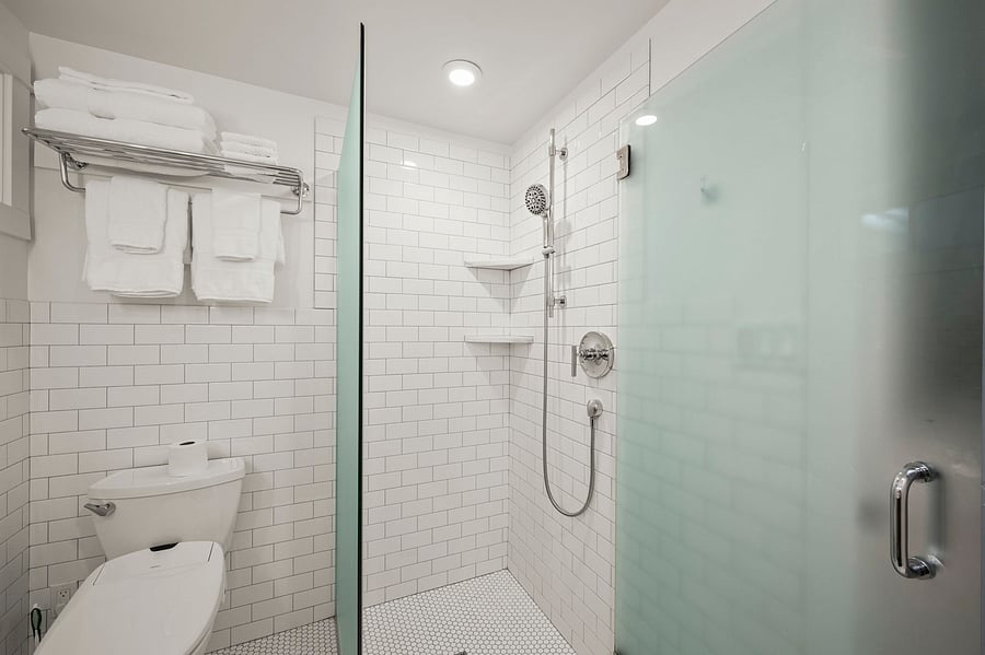 Walk-in shower and bath area with glass enclosure, modern fixtures, and towel storage.