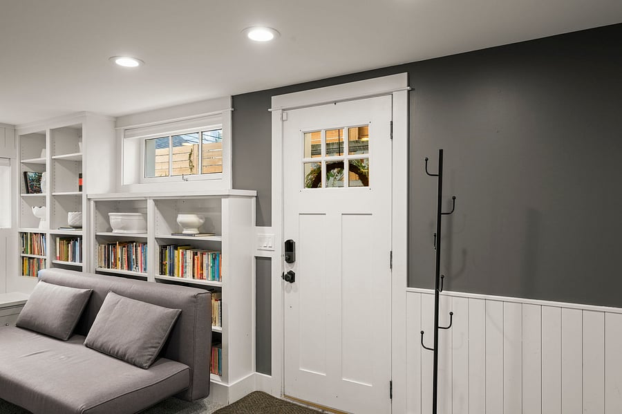 Interior view of private entry door, coat hooks, and built-in seating/bookshelves in main room.