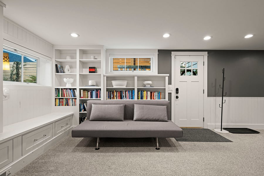 Reverse angle of book-shelf wall and convertible couch looking toward private front entry.