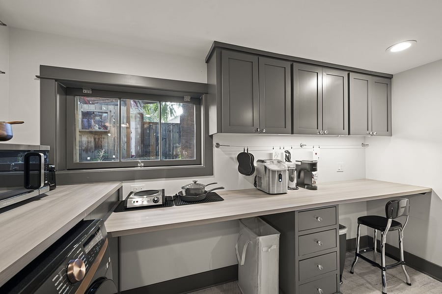 Kitchenette from sink side showing dining island, laundry, ample cabinets, and work space.