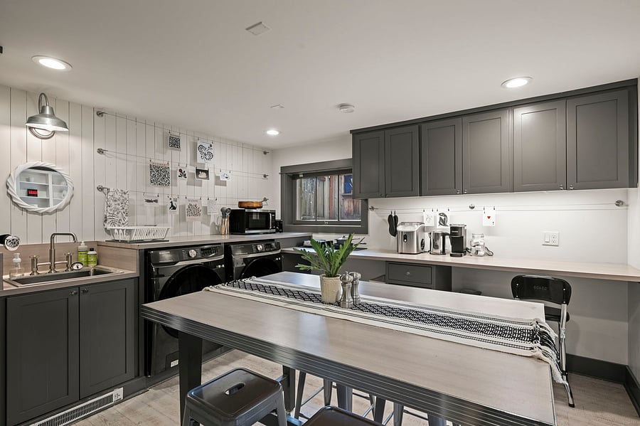 Another view of kitchenette and dining island with in-unit washer/dryer, prep space, and storage cabinetry.