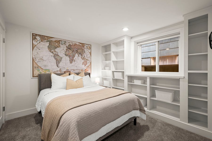 Bedroom from window side showing queen bed, built-ins, and generous storage shelving.
