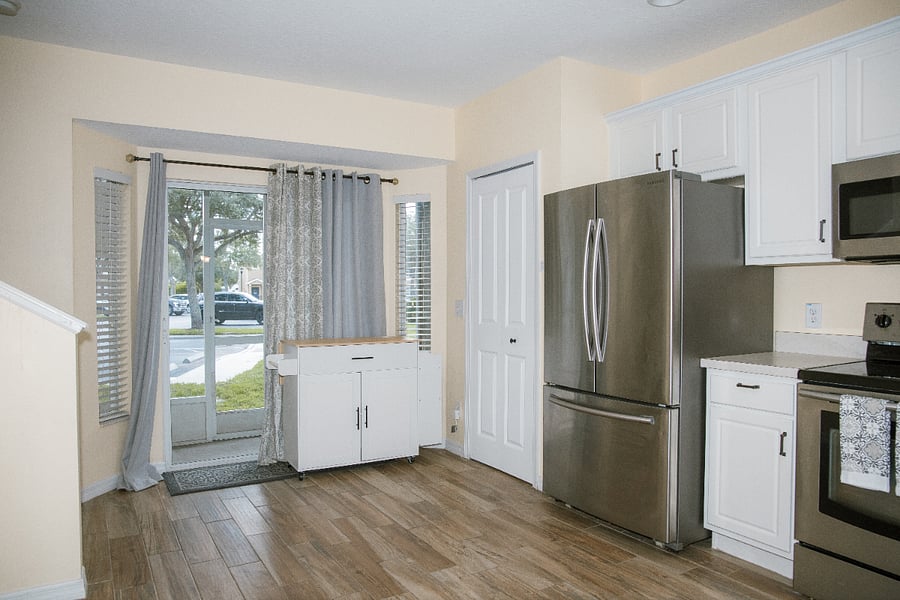 Stainless steel appliances, pantry, and an extra kitchen cart for storage.