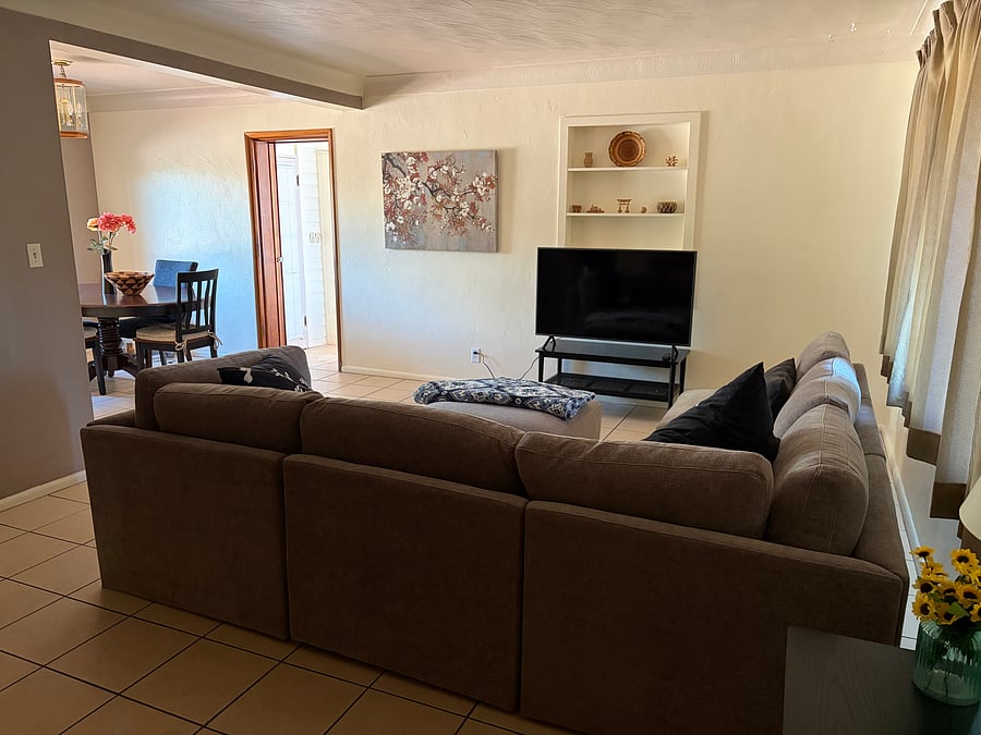 Living room with new couch and SmartTV. Dining room with table and chairs to the left.