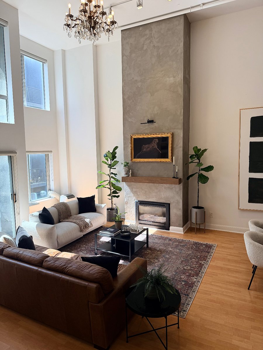 Designer living room with floor to ceiling windows, high ceilings and a beautiful fireplace, mantel and frame tv