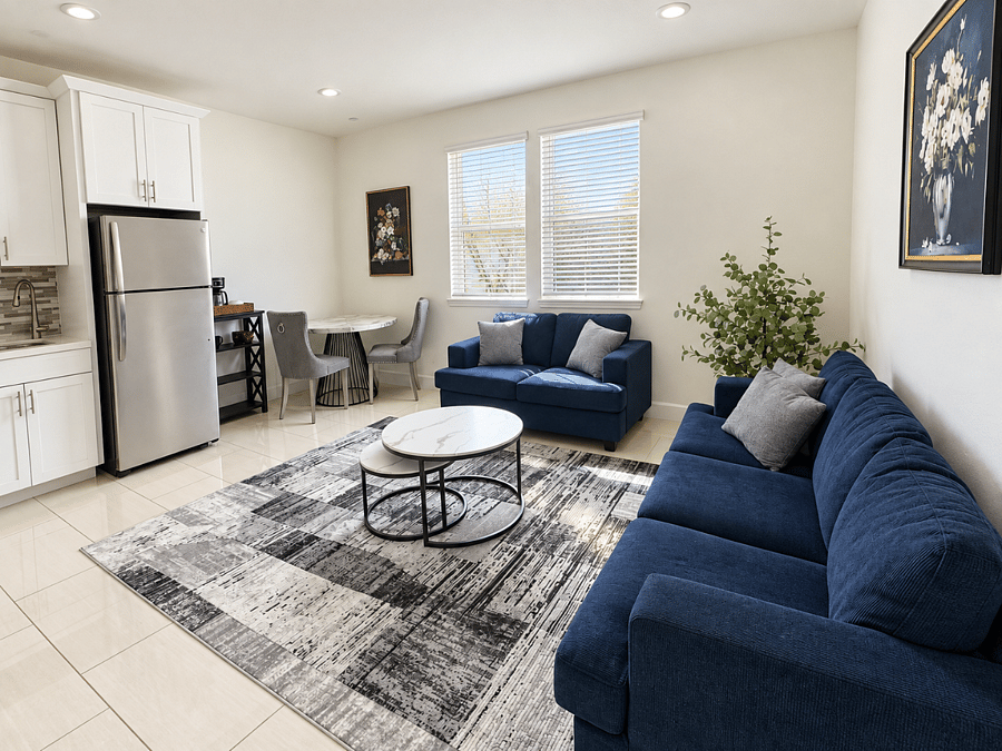 Bright, fully furnished living area with comfortable seating, dining space, and adjoining kitchenette.