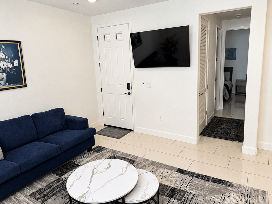 Comfortable furnished living area with wall-mounted Smart TV, private entrance, and easy access to the bedroom and bathroom.