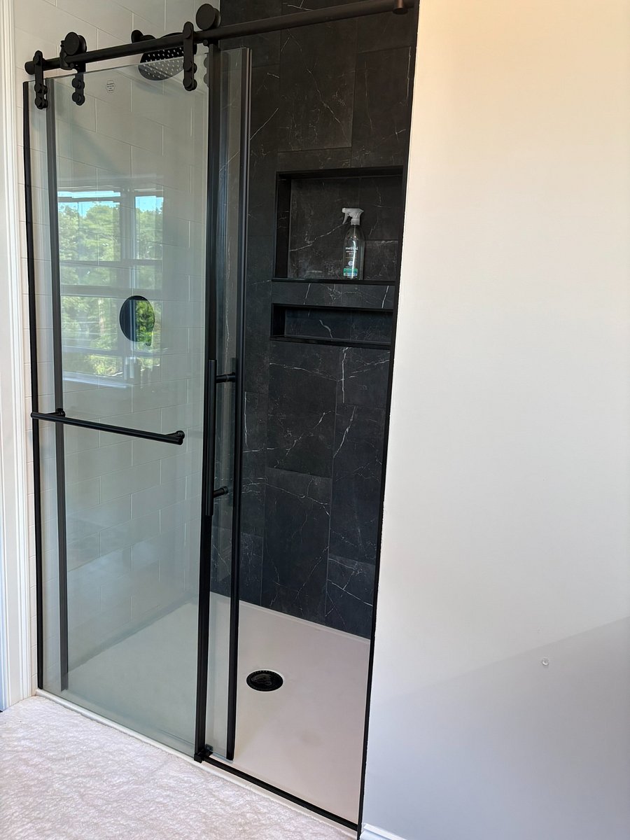 Tile shower with rain shower head in primary bedroom
