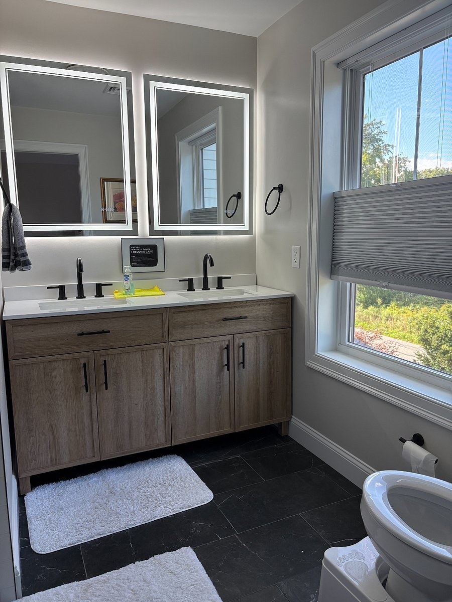 Double vanity with lighted mirrors, in Primary bedroom. Features blackout top down/bottom up shade
