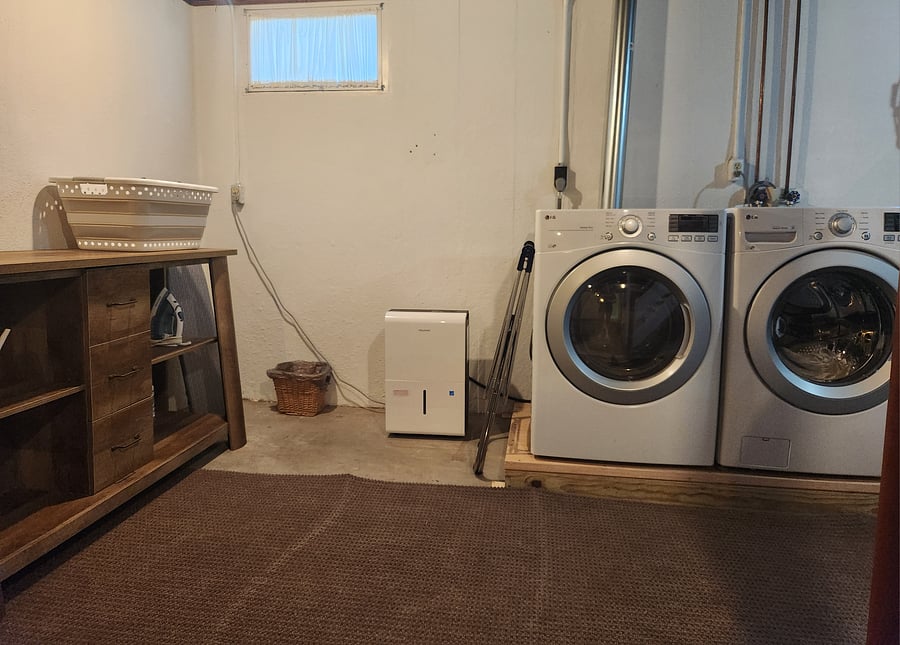 Washer, dryer, drying rack, ironing board, iron, laundry folding surface, laundry basket, and cleaning supplies all located in basement.