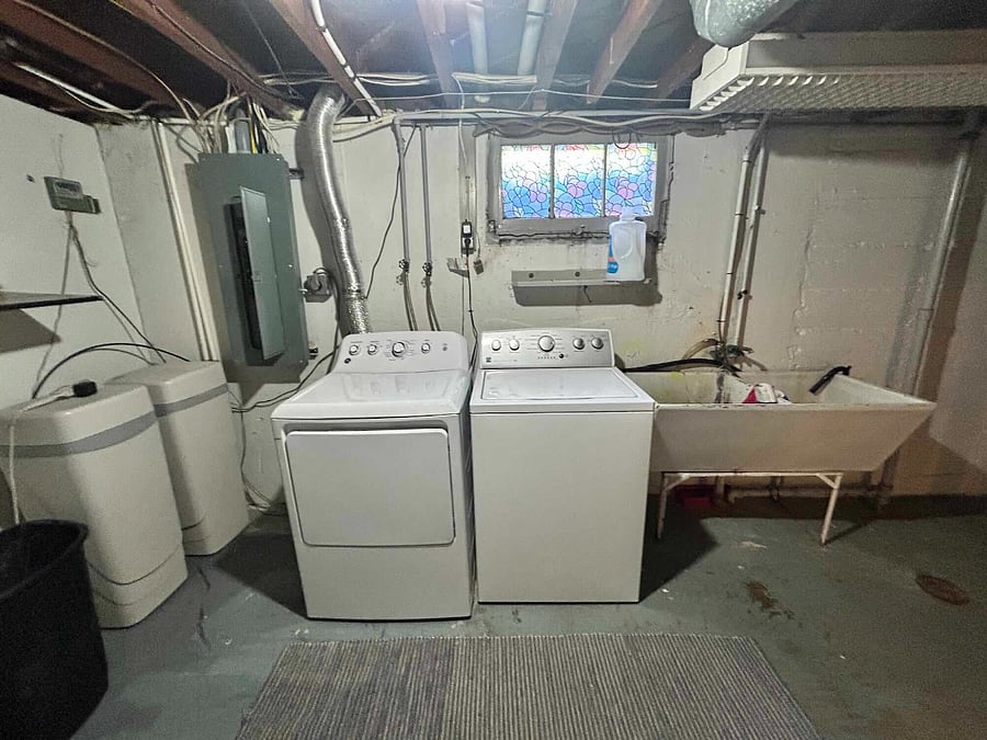 Basement Laundry area with washer and dryer, utility sink, and water softening system. 