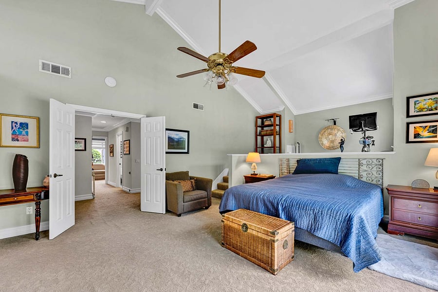 Another angle of your huge Primary Bedroom with soaring high ceilings, lit ceiling fan and more.