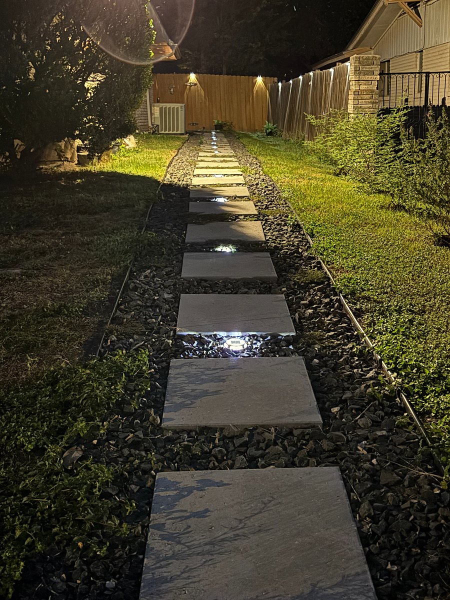 Lighted walkway to private gated entrance at night.