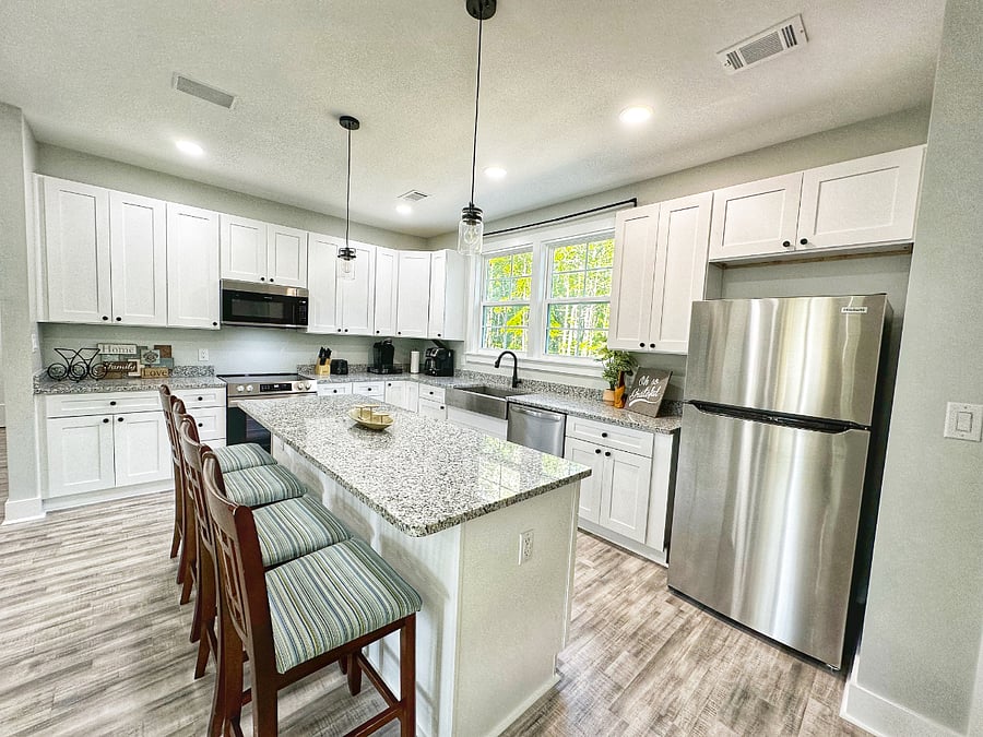 Bright, fully equipped kitchen with granite counters, stainless appliances, and island seating.