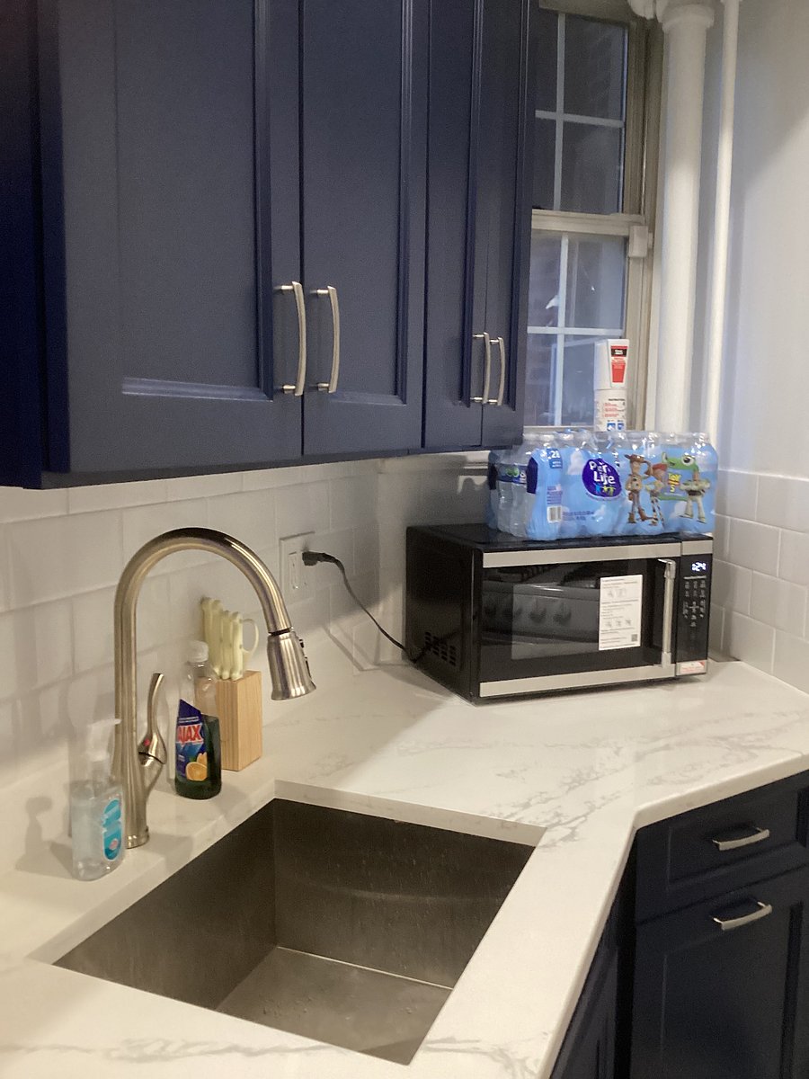 LARGE SINGLE STAINLESS STEEL SINK WITH LARGE ATTACHED SPRAYER AND MICROWAVE. ALSO DOUBLE TRASH CANS STORED UNDERNEATH MICROWAVE.