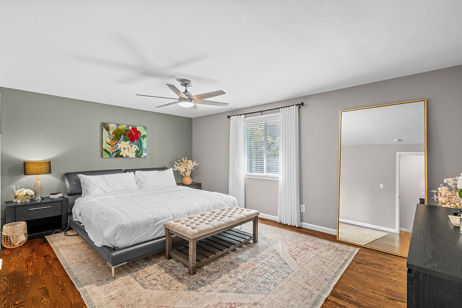 Spacious primary bedroom features a comfortable king size bed and a wall mounted smart TV.