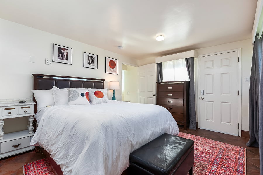 Master Bedroom 1 (Red Suite): Spacious primary bedroom with an attached bathroom, adjustable bed, generous closet storage, and several cabinets