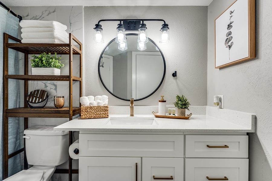 Clean and modern bathroom vanity with chic fixtures and a large circular mirror