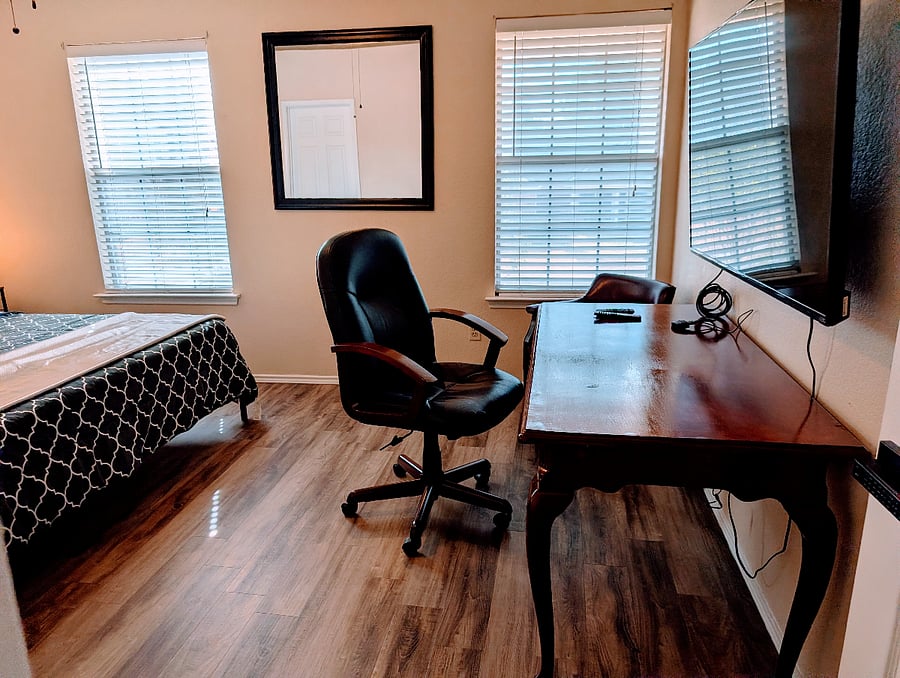 Primary Bathroom with King Bed, Desk, rolling Chair and 55" TV with HDMI that can serve as the second monitor and a ceiling fan.