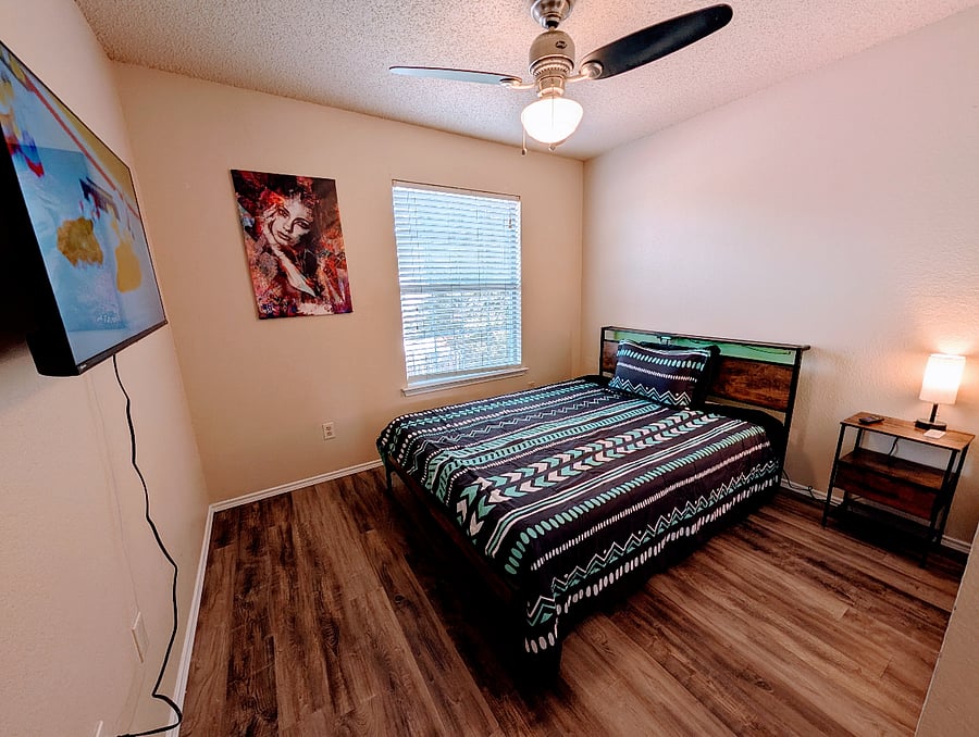 Second bedroom with a queen bed, ceiling fan and a 43" Smart TV.