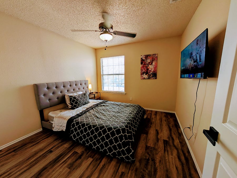 Third bedroom with a queen bed, ceiling fan and a 43" Smart TV.