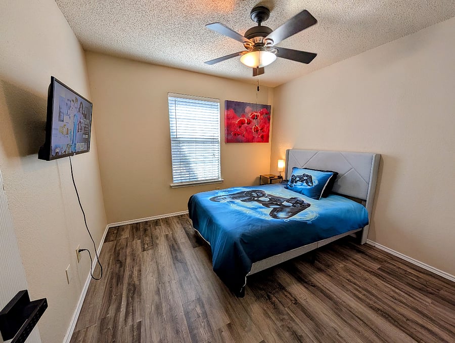 Fourth bedroom with a queen bed, ceiling fan and a 32" Smart TV.
