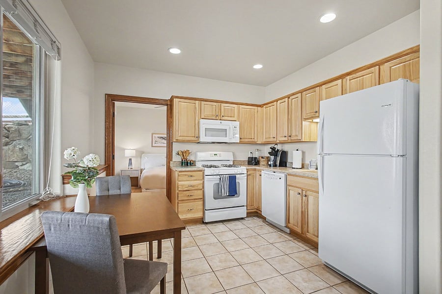 Bright, fully equipped kitchen with full-size appliances, abundant cabinetry, and an inviting dining area overlooking the outdoors. Convenient access to the bedroom completes the functional layout.