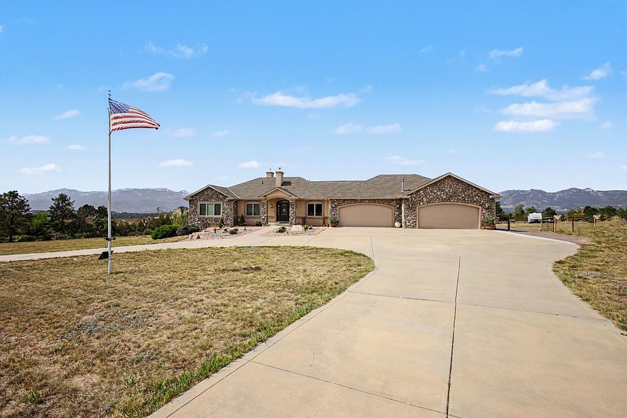 Front view of the spacious main house with an expansive driveway and beautiful mountain backdrop. The private apartment is located around the back of the home and has its own separate exterior entrance.